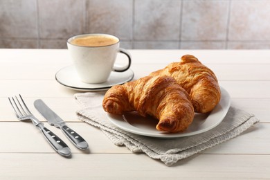 Delicious fresh croissants served with coffee on white wooden table