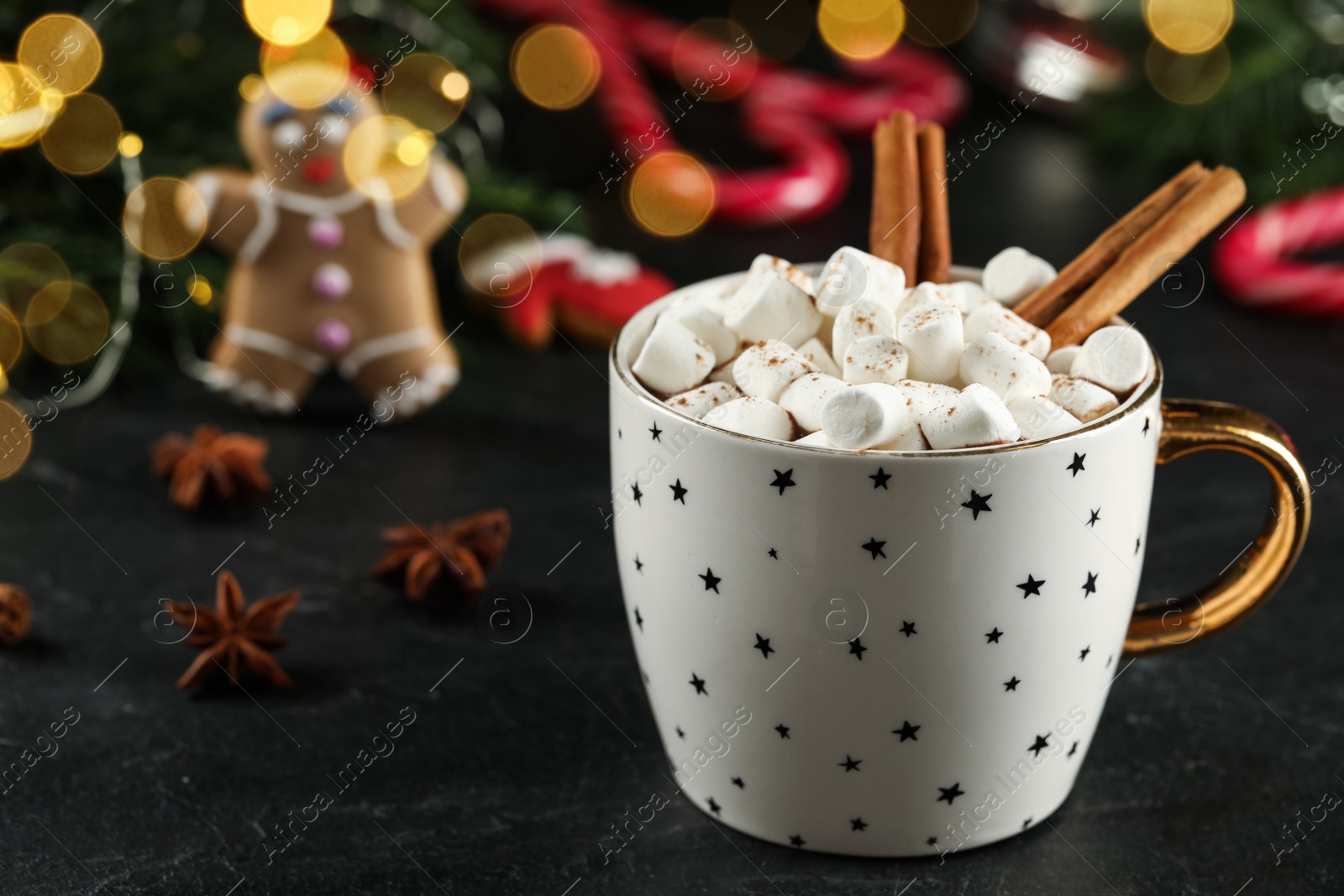 Photo of Delicious hot chocolate with marshmallows and cinnamon near Christmas decor on black table, closeup. Space for text