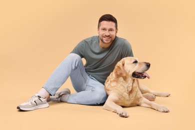 Man with adorable Labrador Retriever dog on beige background. Lovely pet