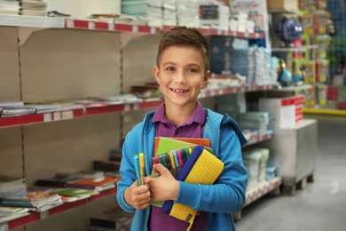 Photo of Little boy choosing school stationery in supermarket