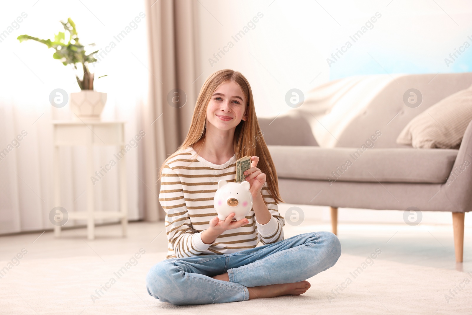 Photo of Teen girl with piggy bank and money at home