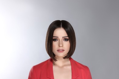Portrait of stylish young woman with brown hair on grey background