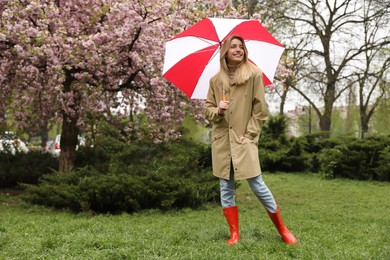 Photo of Young woman with umbrella in park on spring day