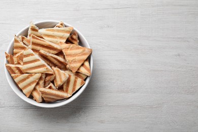 Photo of Delicious pita chips on white wooden table, top view. Space for text