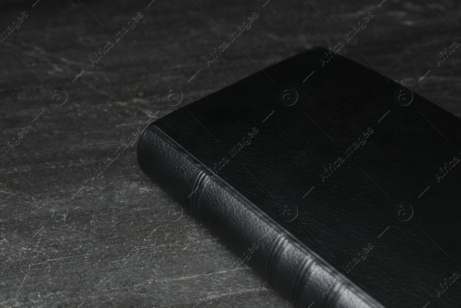 Photo of Bible on black table, closeup. Christian religious book