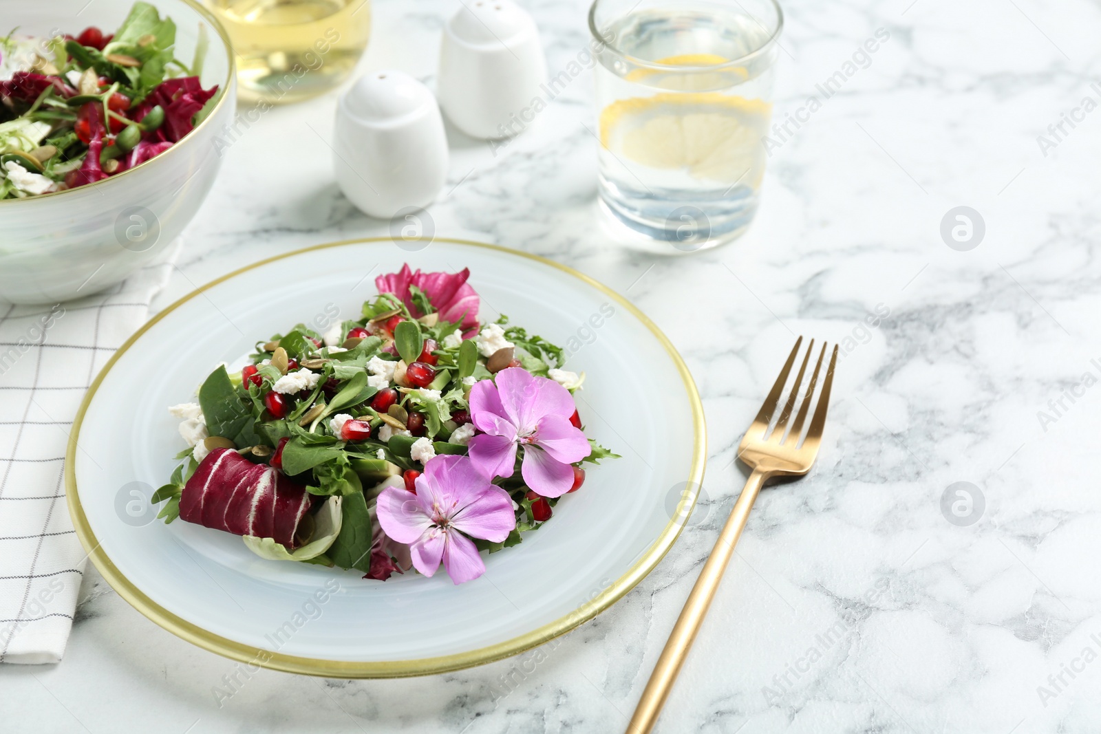 Photo of Fresh spring salad with flowers served on white marble table