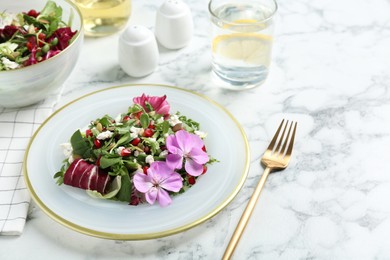 Fresh spring salad with flowers served on white marble table