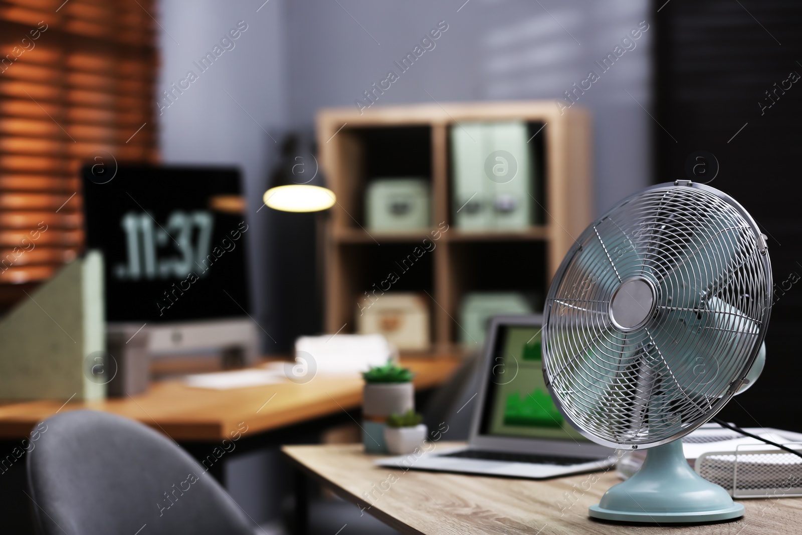 Photo of Modern electric fan on table in office. Space for text