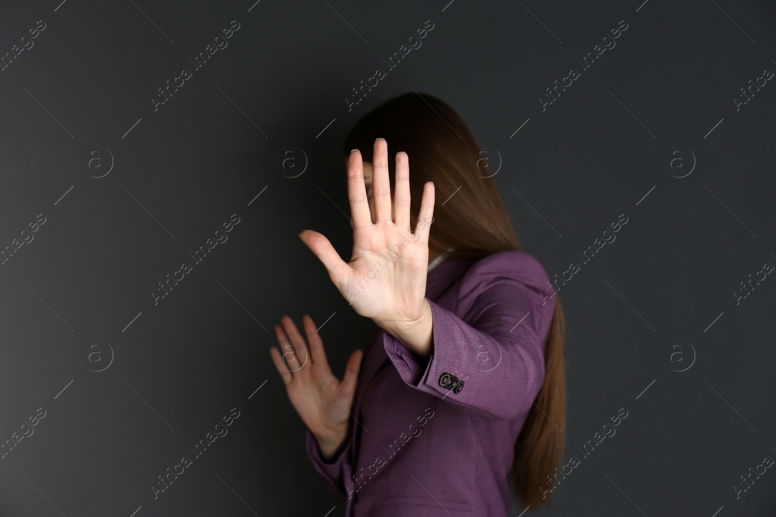 Photo of Woman showing stop gesture on dark background. Problem of sexual harassment at work