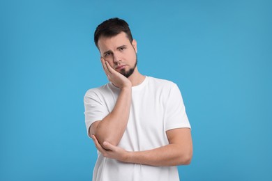 Portrait of sad man on light blue background