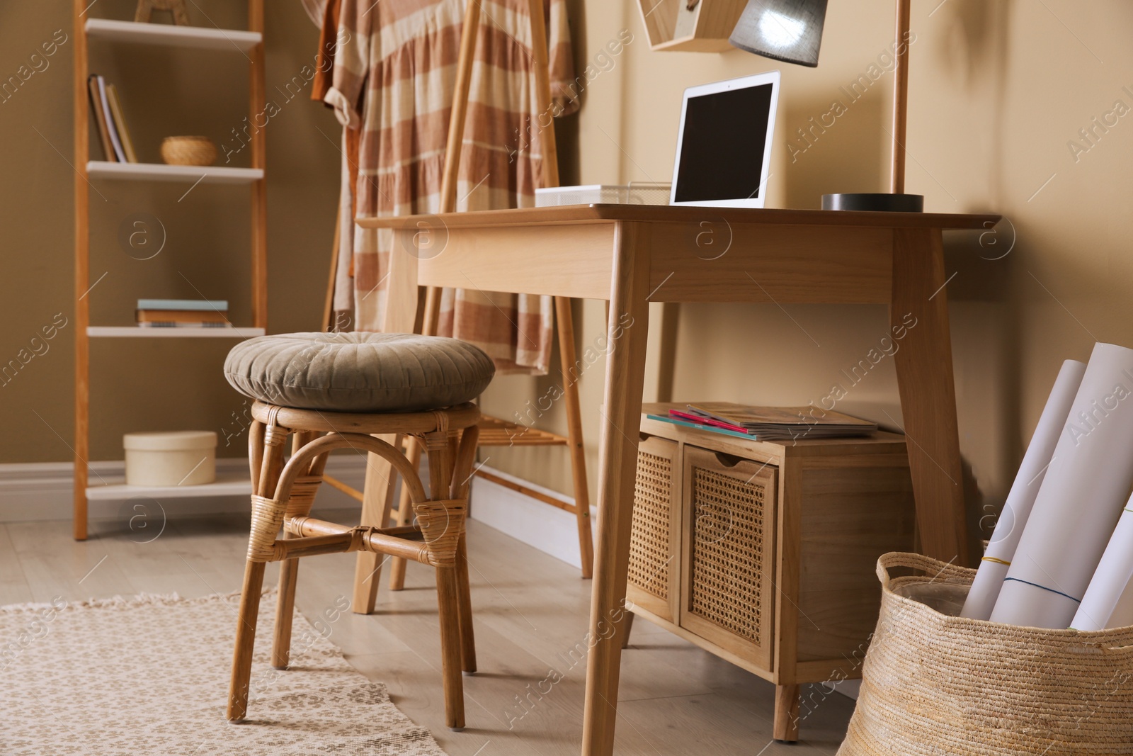 Photo of Comfortable wooden stool near table with laptop indoors. Interior design