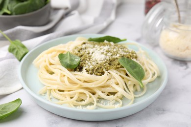 Photo of Tasty pasta with spinach, cheese and sauce on white marble table