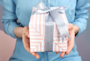 Photo of Young woman holding beautifully decorated gift box, closeup