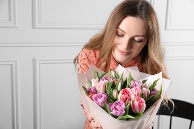 Photo of Young woman with bouquet of beautiful tulips indoors. Space for text