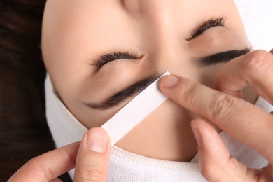 Photo of Young woman having professional eyebrow correction procedure, closeup