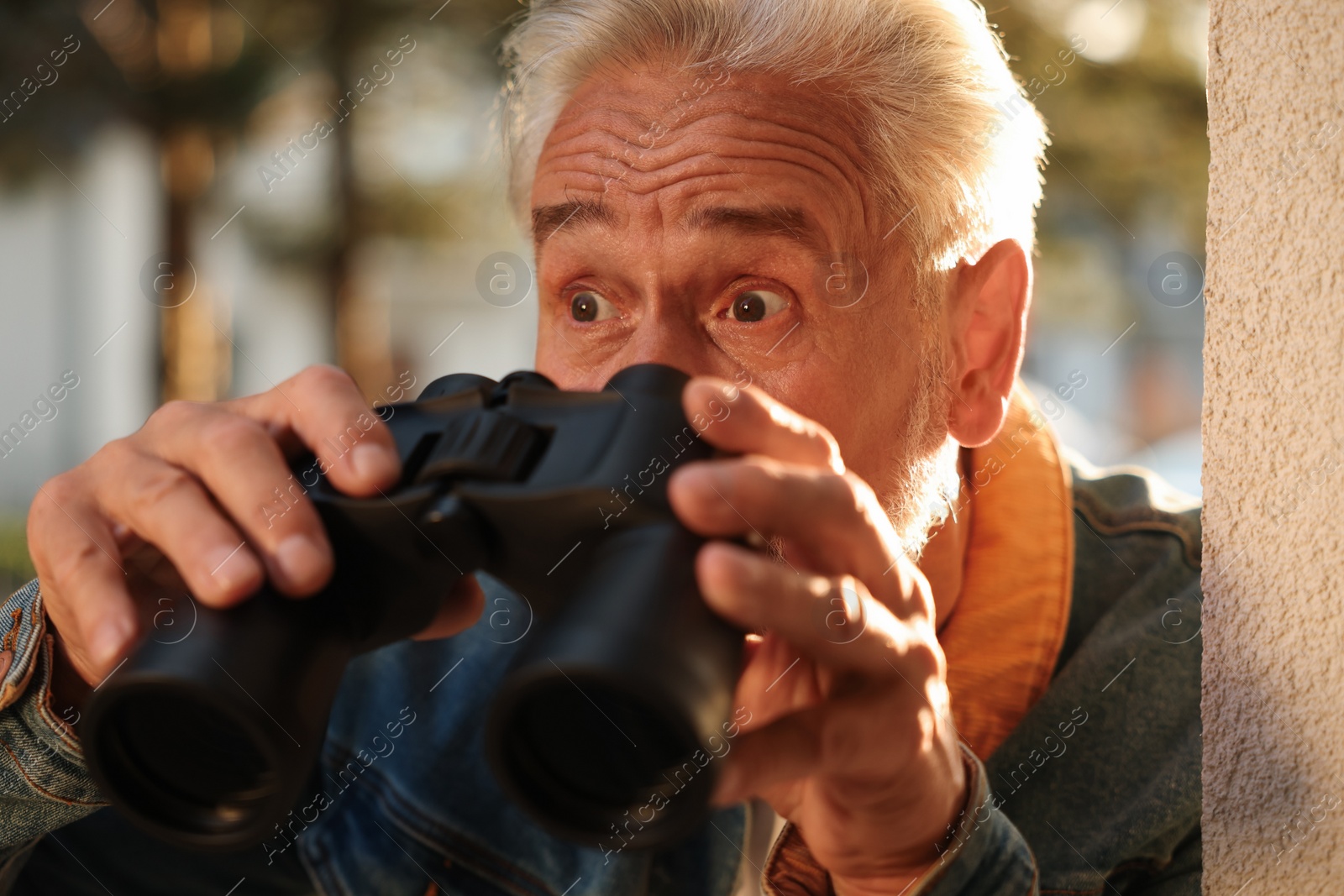 Photo of Concept of private life. Curious senior man with binoculars spying on neighbours outdoors, closeup