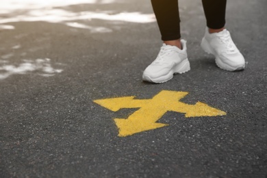 Photo of Woman standing near arrow on asphalt, closeup