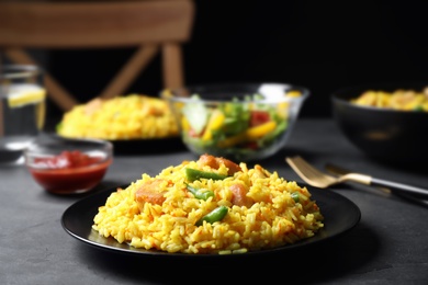 Photo of Delicious rice pilaf with meat served on dark table, closeup. Space for text