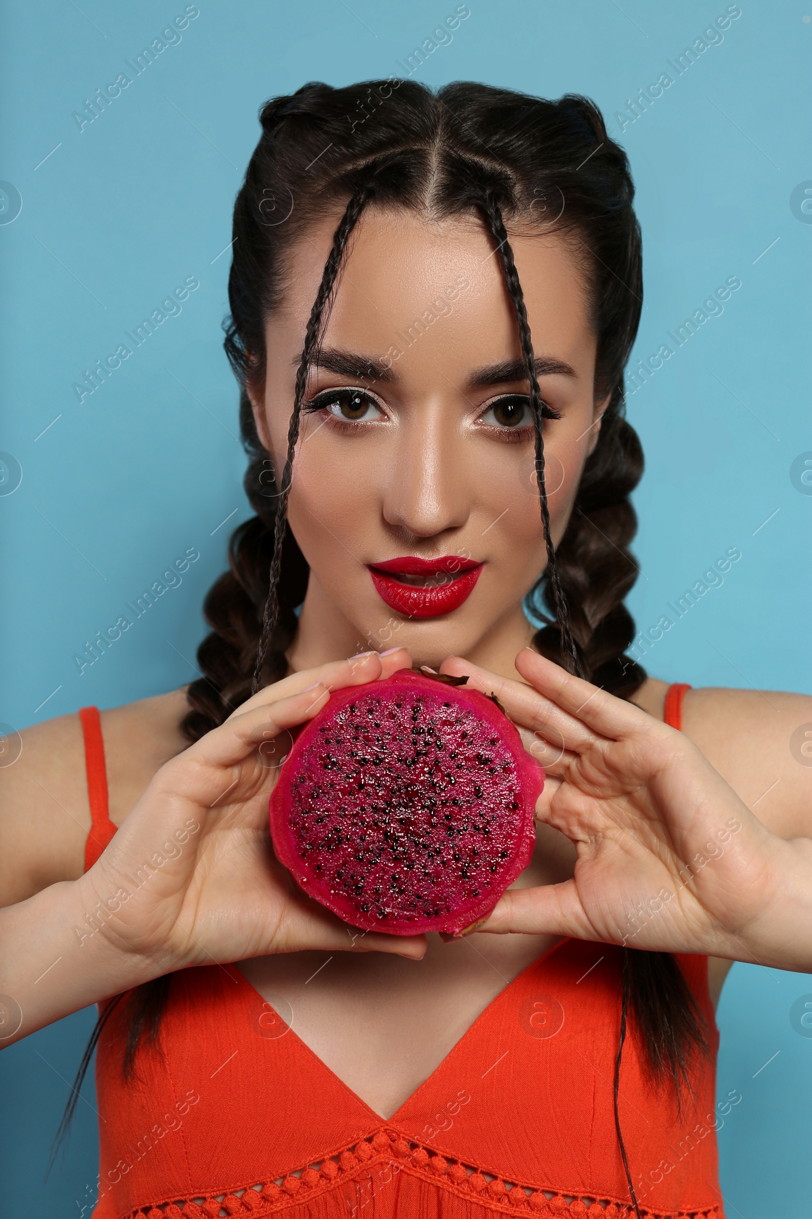 Photo of Young woman with fresh pitahaya on light blue background. Exotic fruit