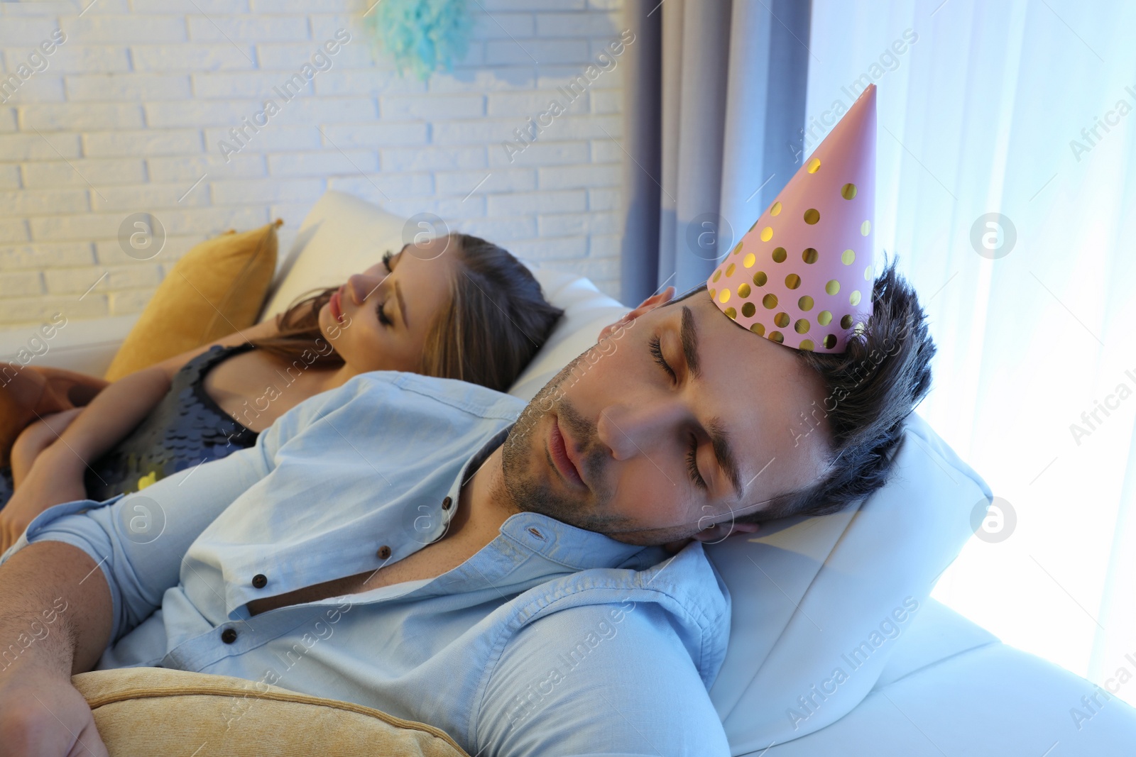 Photo of Drunk friends sleeping on sofa in room after party