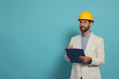 Professional engineer in hard hat with clipboard on light blue background, space for text