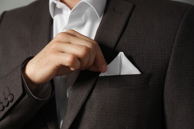 Photo of Man fixing handkerchief in breast pocket of his suit, closeup