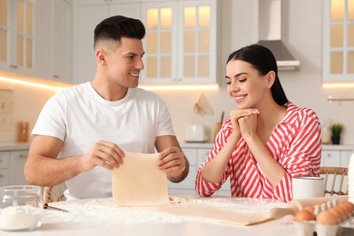 Photo of Happy couple wearing pyjamas and cooking together in kitchen