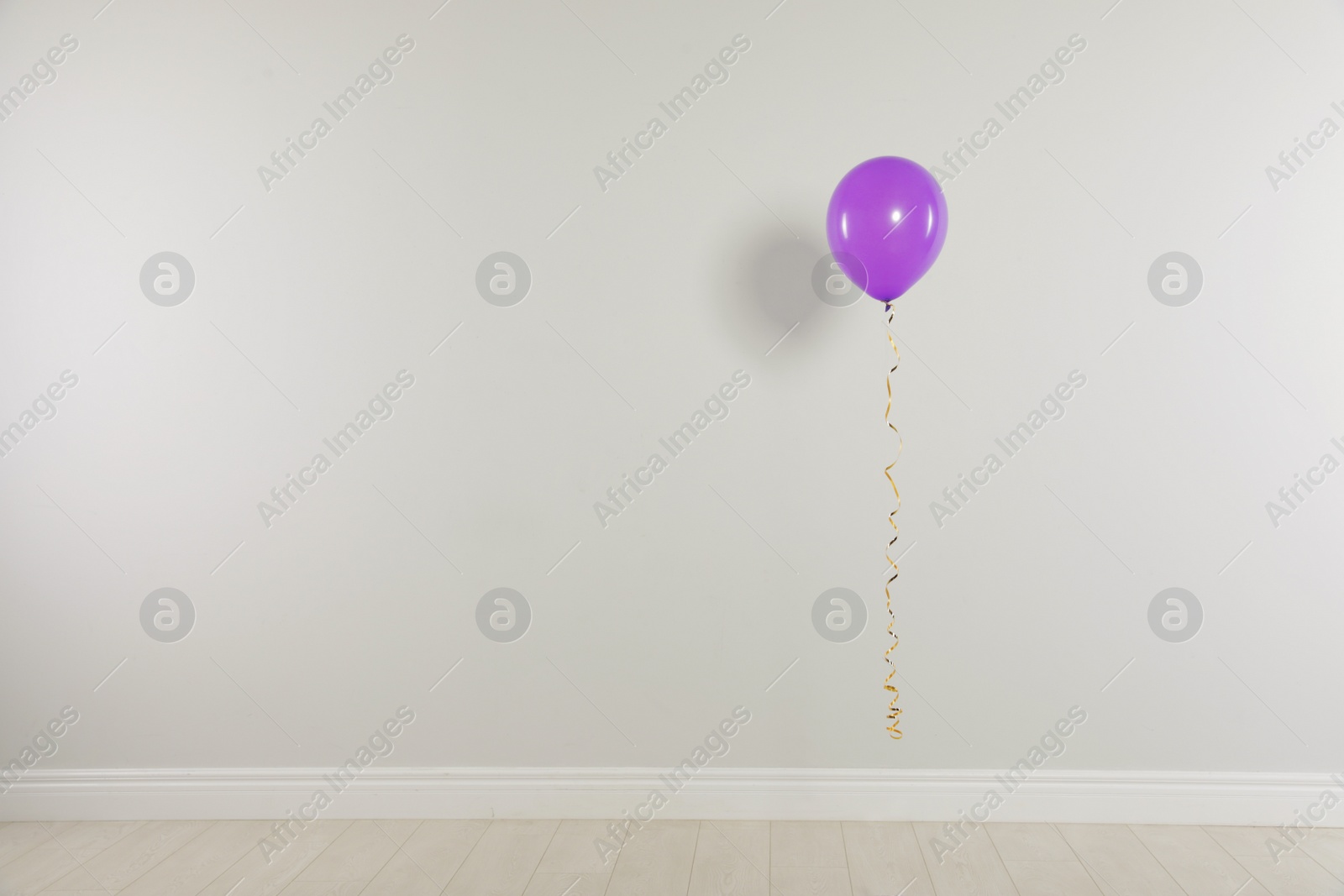 Photo of Bright balloon against light wall, space for text. Celebration time