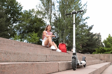 Young woman with backpack outdoors, focus on electric kick scooter