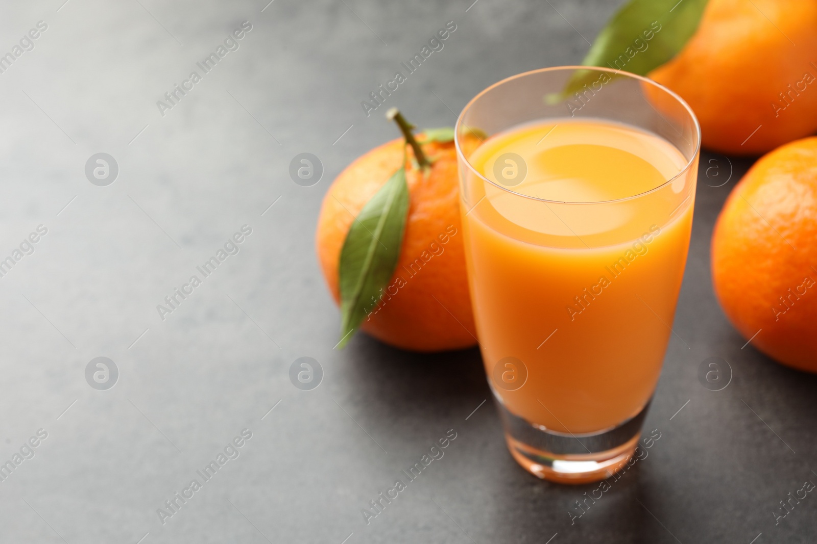 Photo of Delicious tangerine liqueur and fresh fruits on grey table, closeup. Space for text