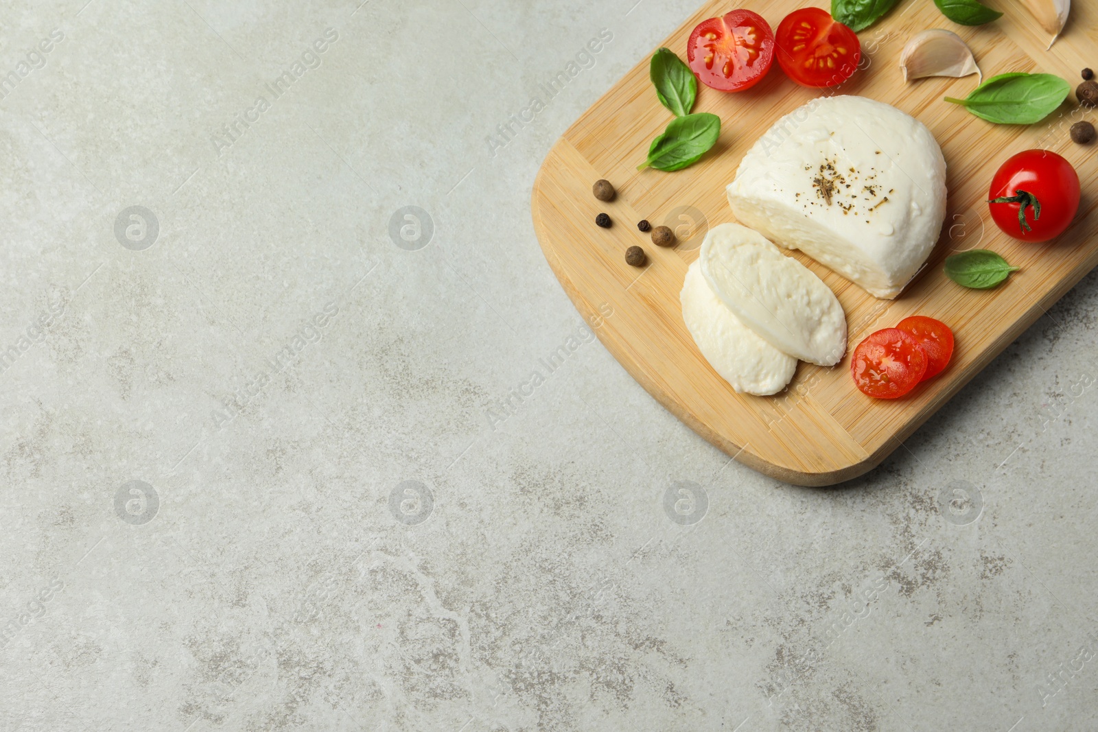 Photo of Delicious mozzarella with tomatoes and basil leaves on light gray table, top view. Space for text