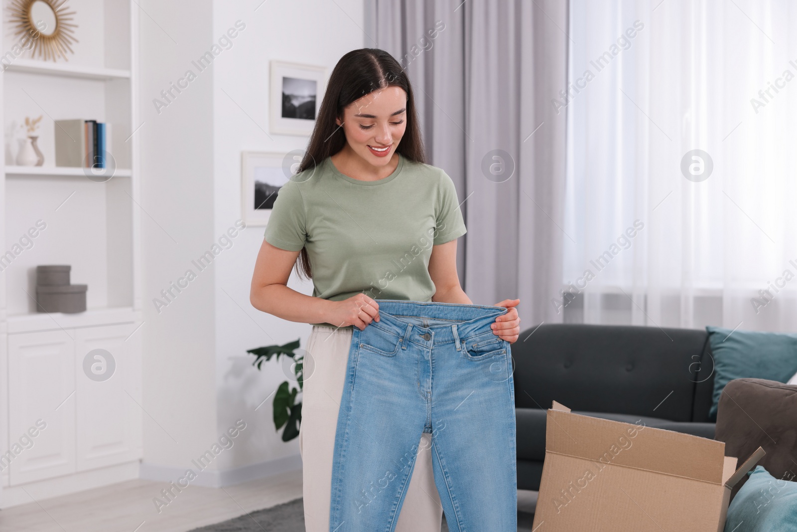 Photo of Happy woman with stylish light blue jeans at home. Online shopping