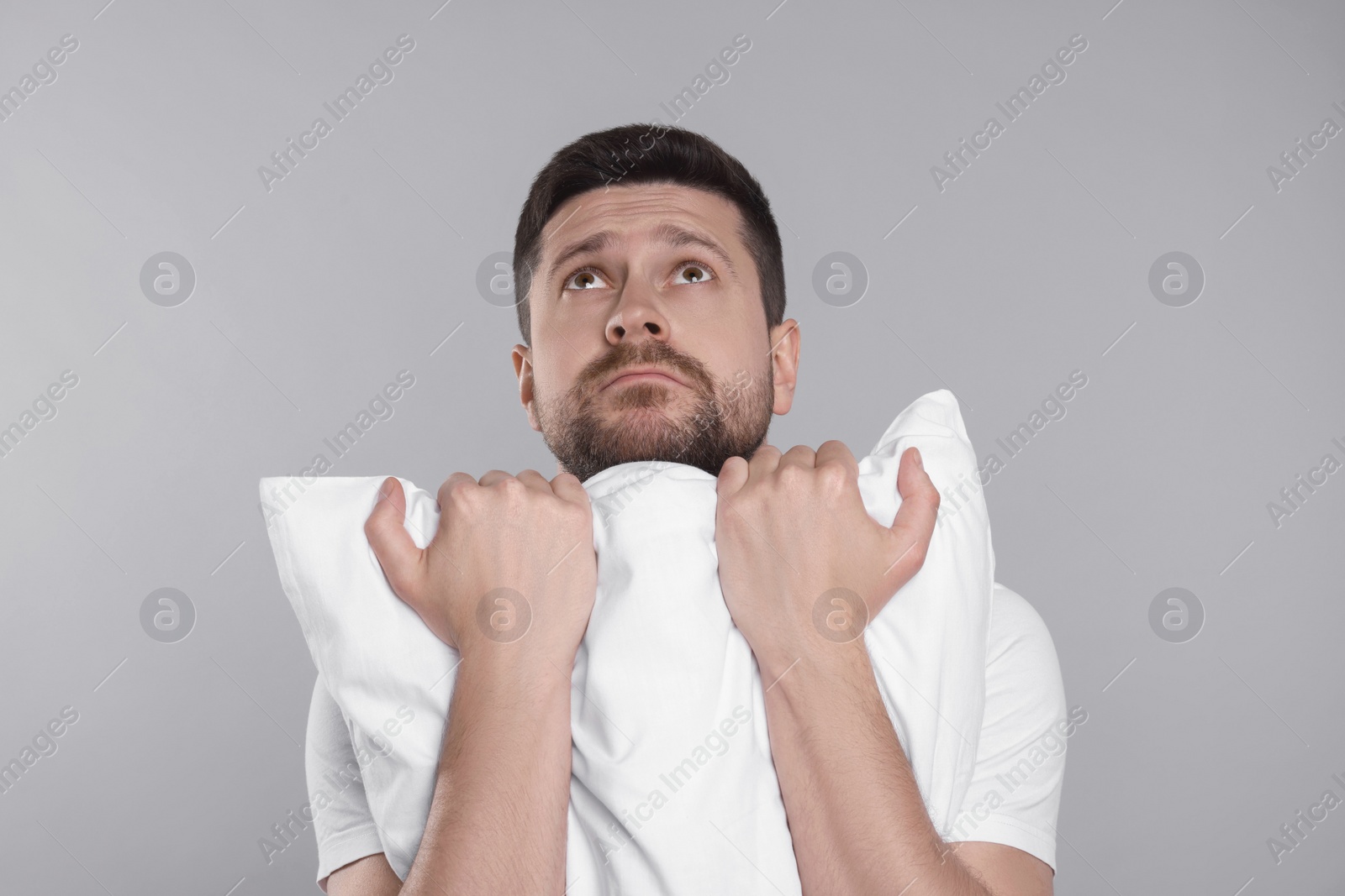 Photo of Sleepy man with pillow on grey background. Insomnia problem