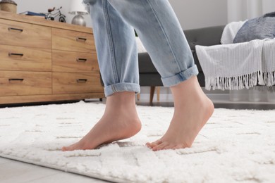 Woman standing on beige carpet in room, closeup