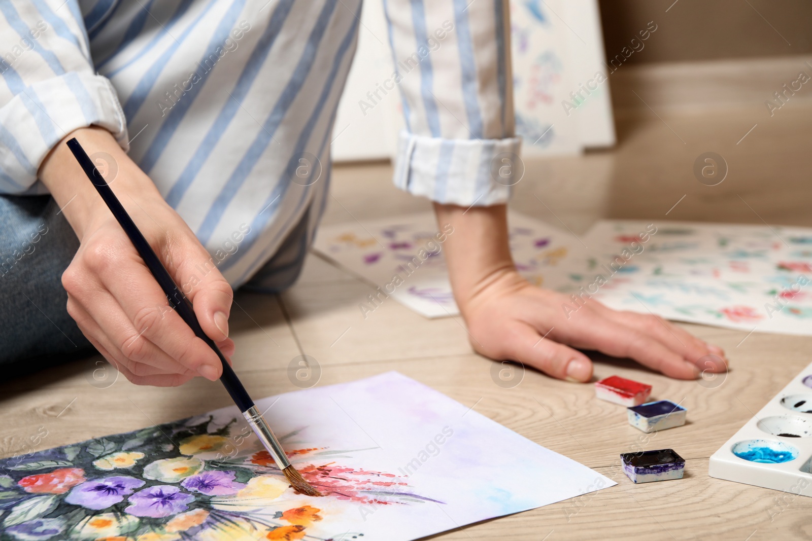 Photo of Woman painting flowers with watercolor on floor, closeup