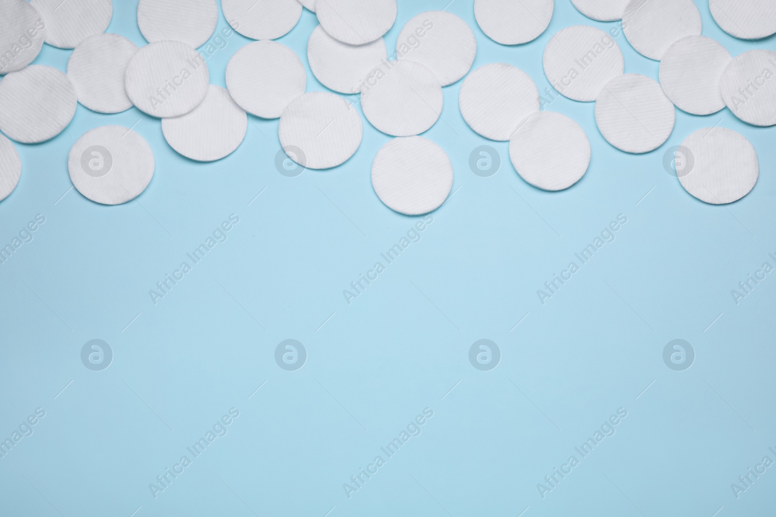 Photo of Many cotton pads on light blue background, flat lay. Space for text