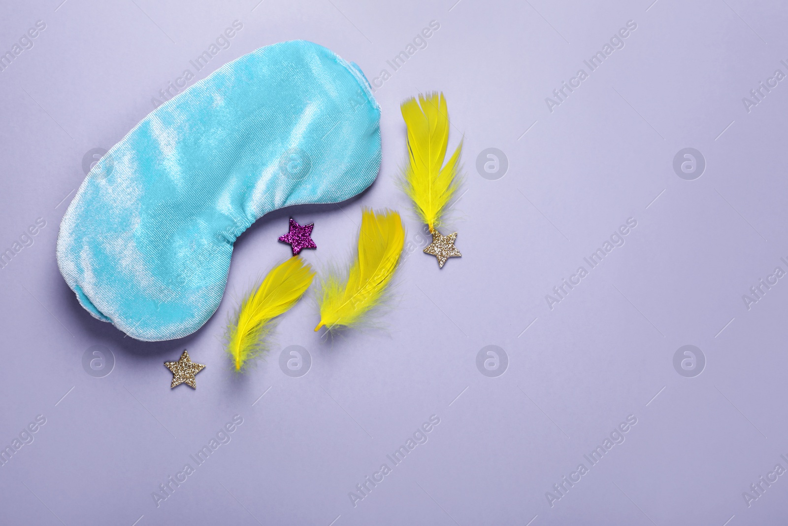 Photo of Soft sleep mask, confetti in shape of stars and feathers on purple background, flat lay. Space for text