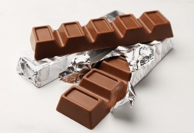 Tasty chocolate bars on white table, closeup