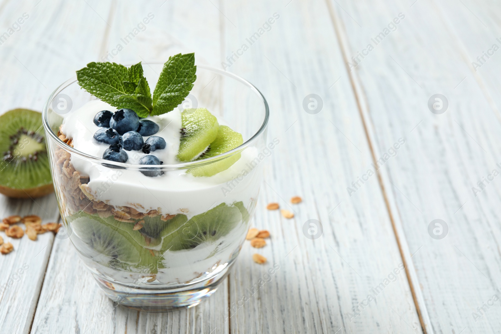 Photo of Tasty homemade granola dessert on white wooden table, space for text. Healthy breakfast