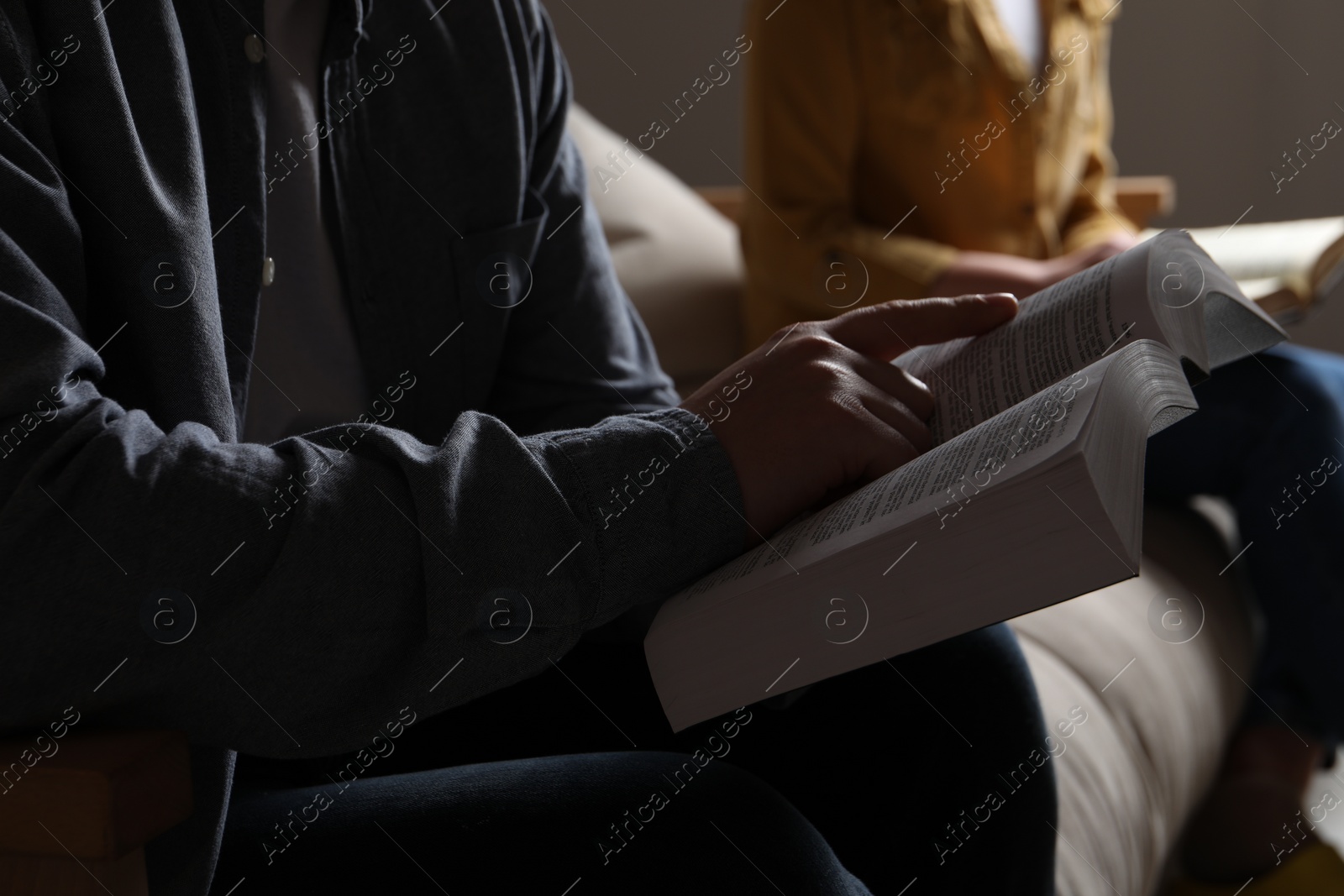 Photo of Couple sitting and reading holy Bible indoors, closeup
