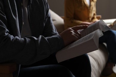 Couple sitting and reading holy Bible indoors, closeup
