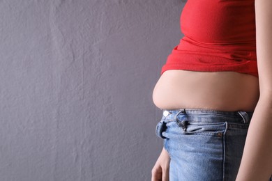 Photo of Woman wearing tight clothes on grey background, closeup view with space for text. Overweight problem