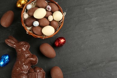 Photo of Flat lay composition with chocolate Easter bunny and eggs on black table. Space for text