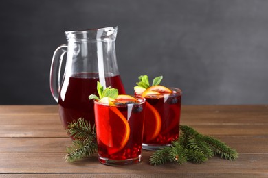 Photo of Aromatic Christmas Sangria drink and fir branches on wooden table