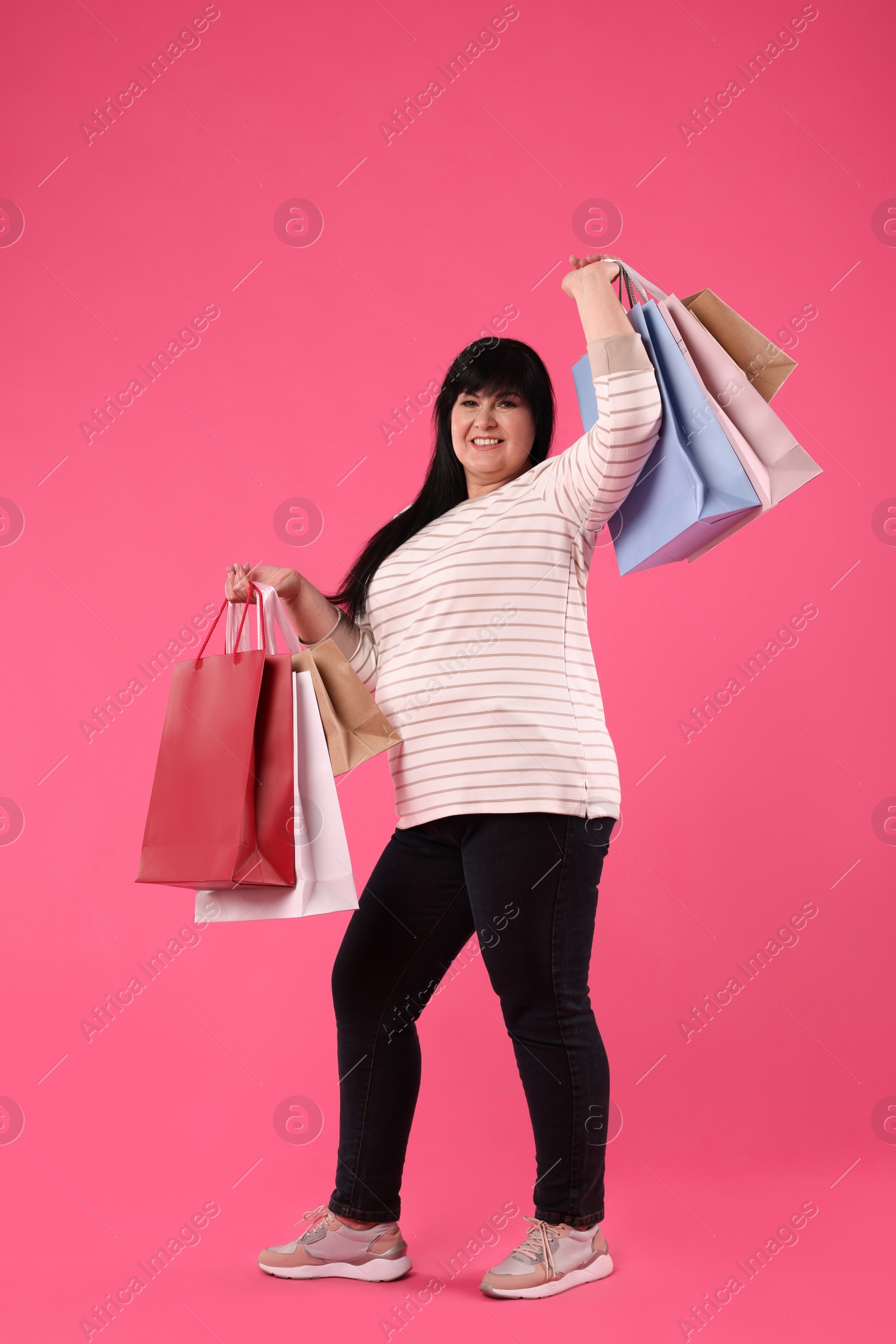 Photo of Beautiful overweight mature woman with shopping bags on pink background