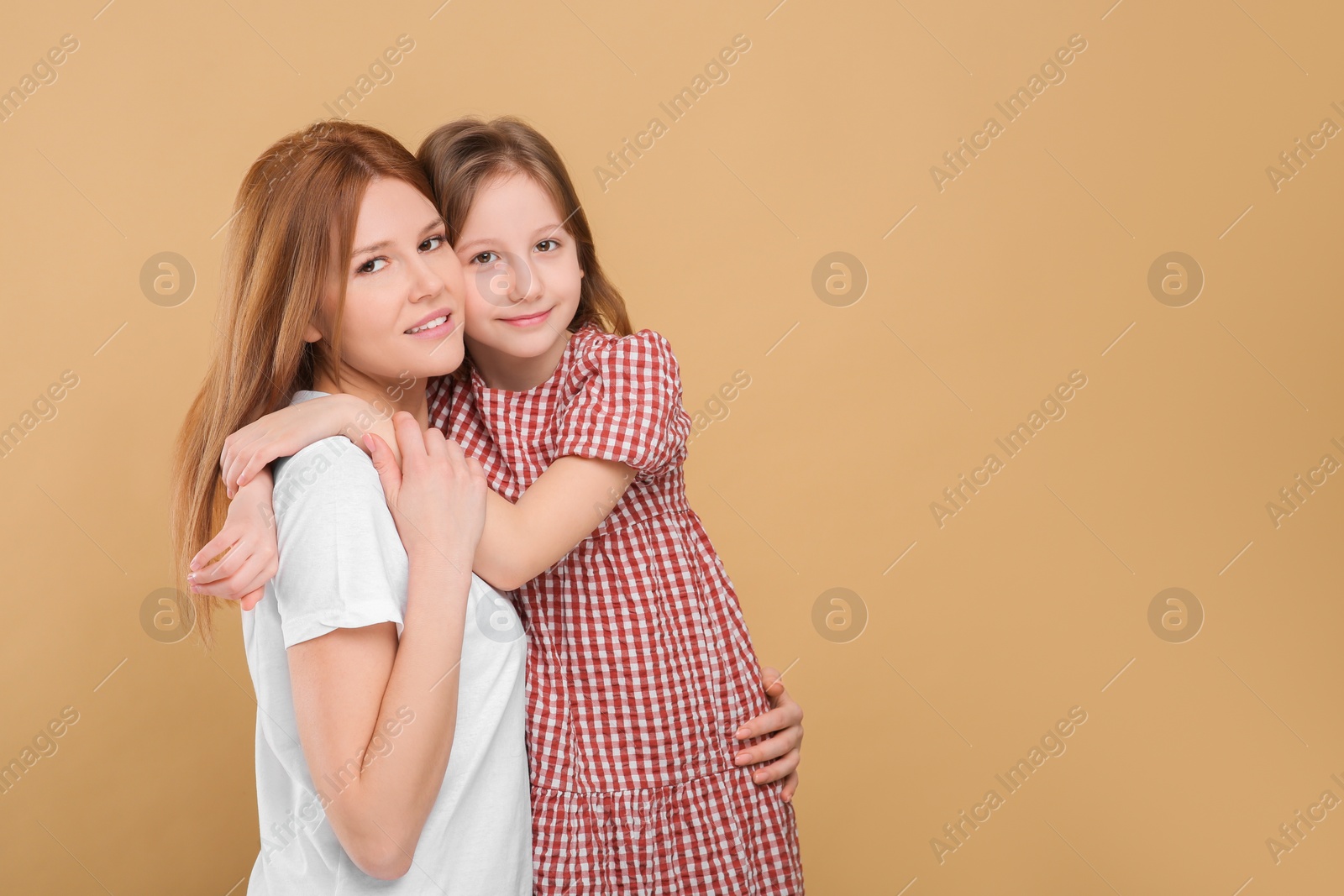 Photo of Portrait of mother and her cute daughter on beige background. Space for text