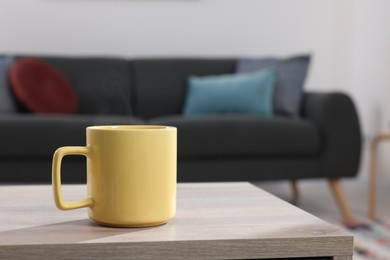 Photo of Yellow mug on wooden table indoors, space for text