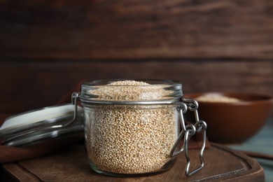 Jar with white quinoa on wooden board