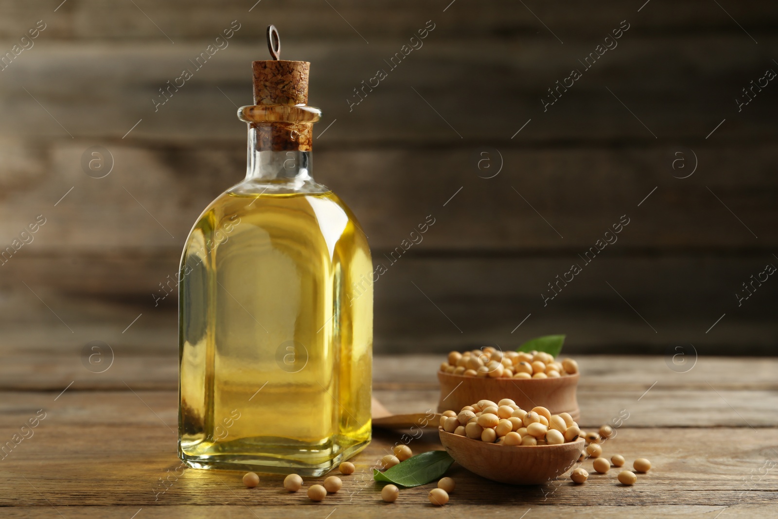 Photo of Glass bottle of oil and soybeans on wooden table