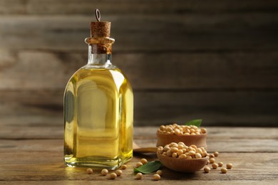Photo of Glass bottle of oil and soybeans on wooden table